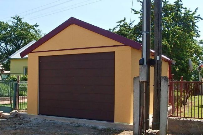 Eine gelbe Satteldach-Garage mit braunem Sektionaltor von Hörmann