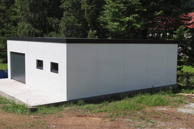 Ein montierter Lagerraum aus Stahl in weiß mit einem Tor in anthrazit