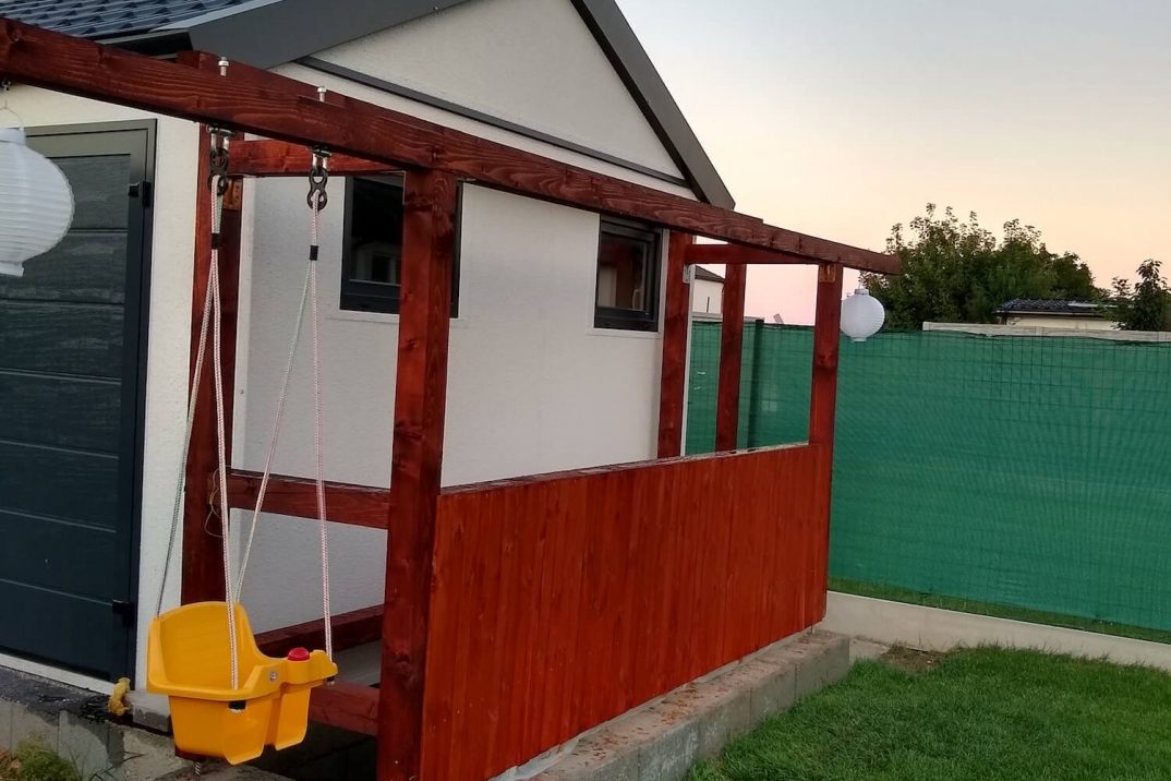 Eine Schaukel an einer Holzüberdachung neben der Garage von GARDEON