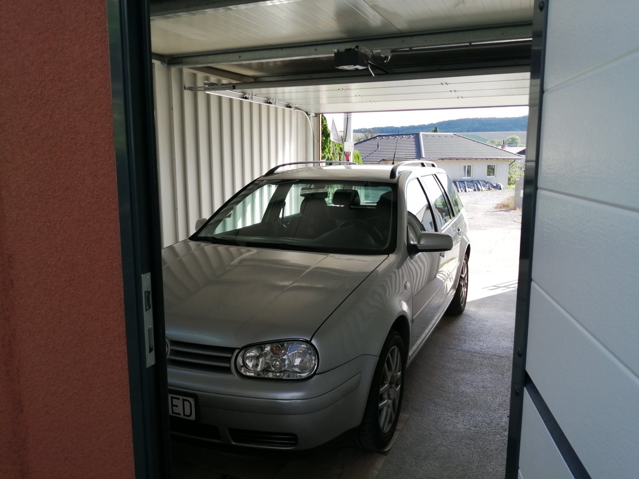 Ein Auto parkt in der ungedämmten Garage mit Durchgang ins Haus