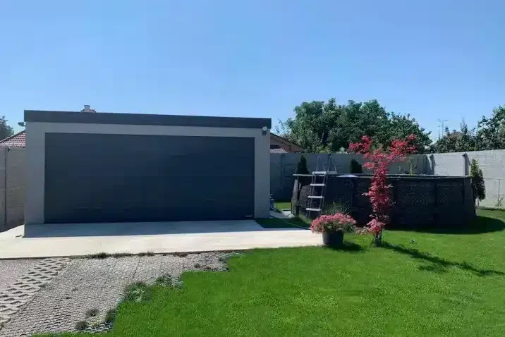 Eine GARDEON Garage mit Fertigputz in einem gepflegten Garten