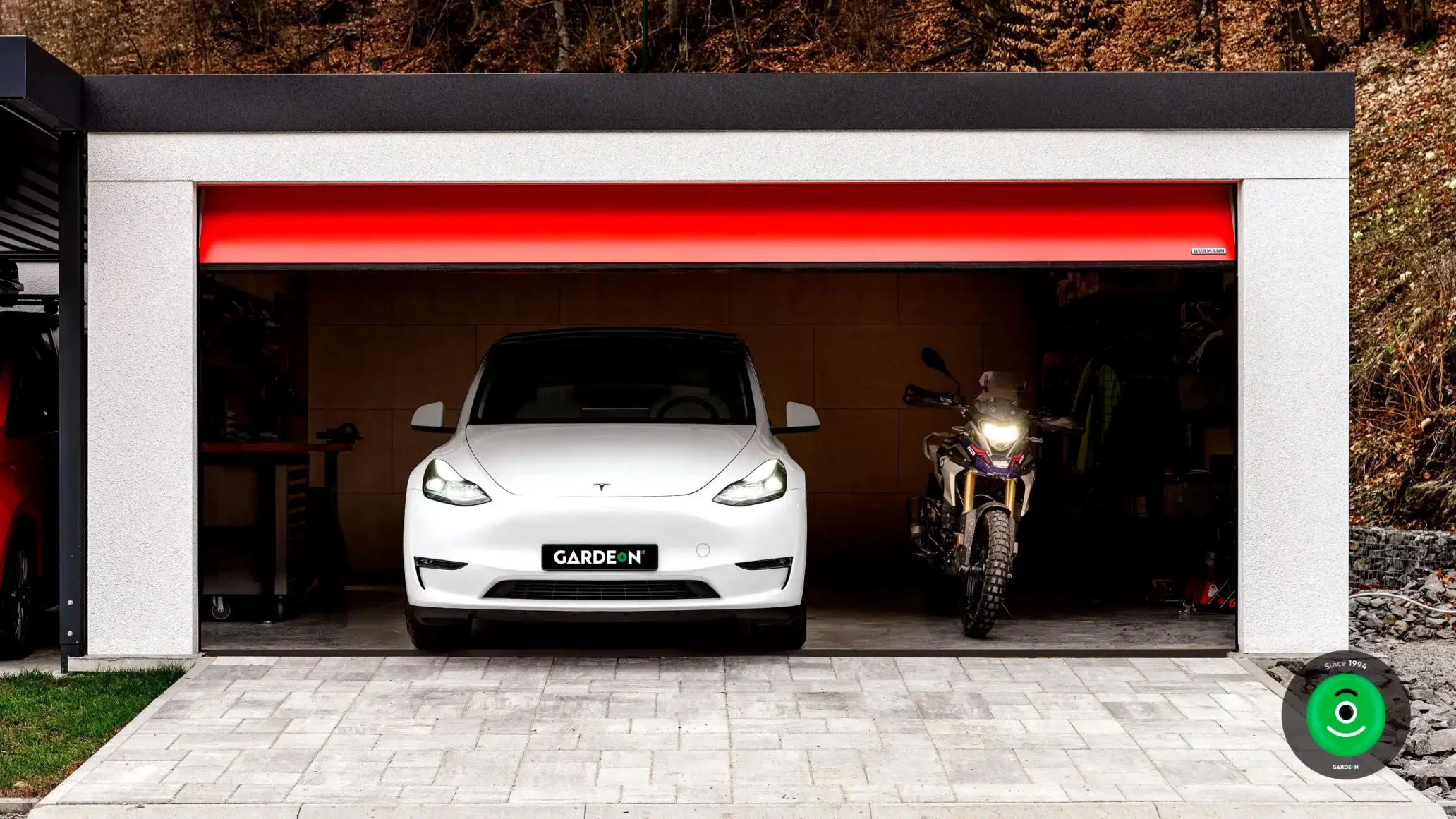 Tesla und Motorrad in der GARDEON-Garage mit rotem Tor