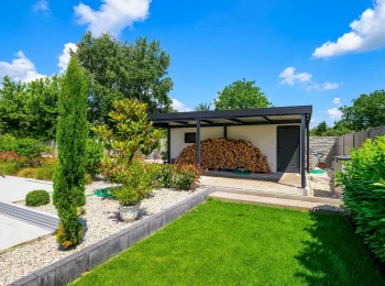 Garage mit zusätzlicher Überdachung in einem großen, grünen Garten