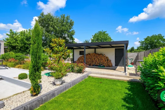 Garage mit zusätzlicher Überdachung in einem großen, grünen Garten