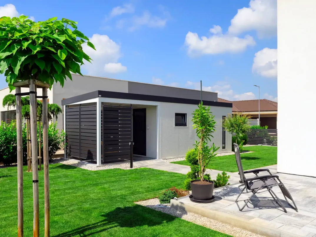 Ein Gartenhaus mit Pergola in einer schönen, grünen Umgebung