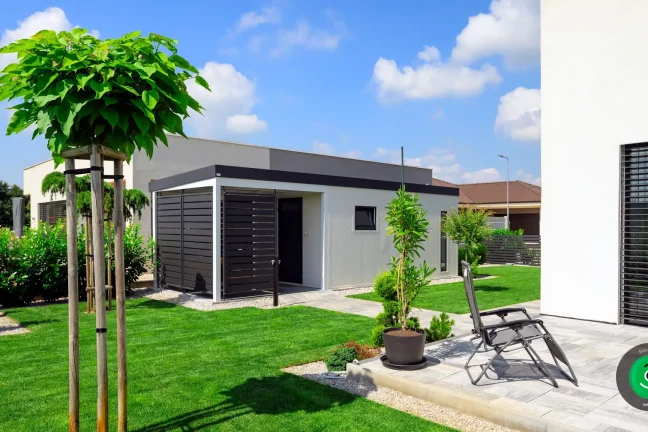 Ein Gartenhaus mit Pergola in einer schönen, grünen Umgebung