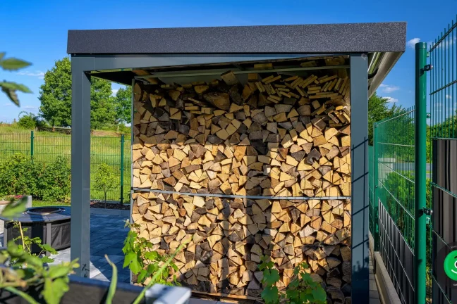 Holz lagert unter der Überdachung am Gartenhaus