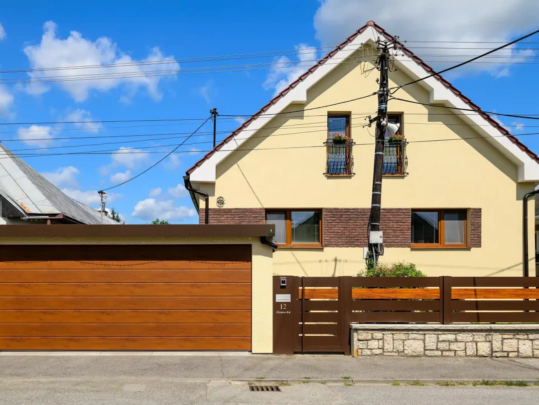 Ein Fertiggarage mit gelbem Putz und breitem braunem Garagentor.