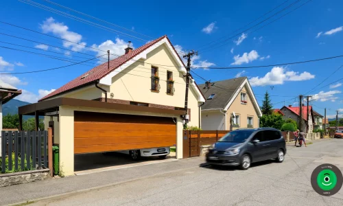 Eleganter Carport mit braunem Tor und gelbem Putz, der das Fahrzeug schützt.