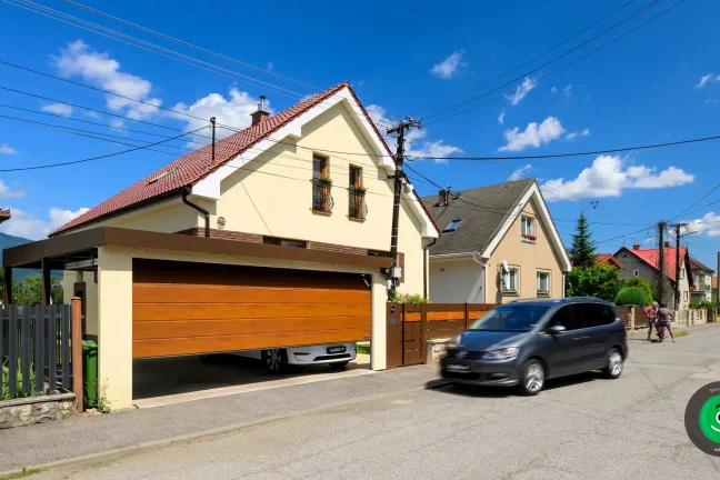 Eleganter Carport mit braunem Tor und gelbem Putz, der das Fahrzeug schützt.