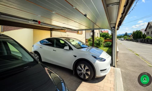 Zwei Autos sicher unter einem Carport mit braunem Garagentor geparkt.