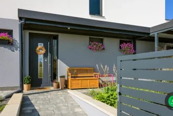 Kleine Überdachung vor der Tür mit einer Holzbank zum Sitzen.