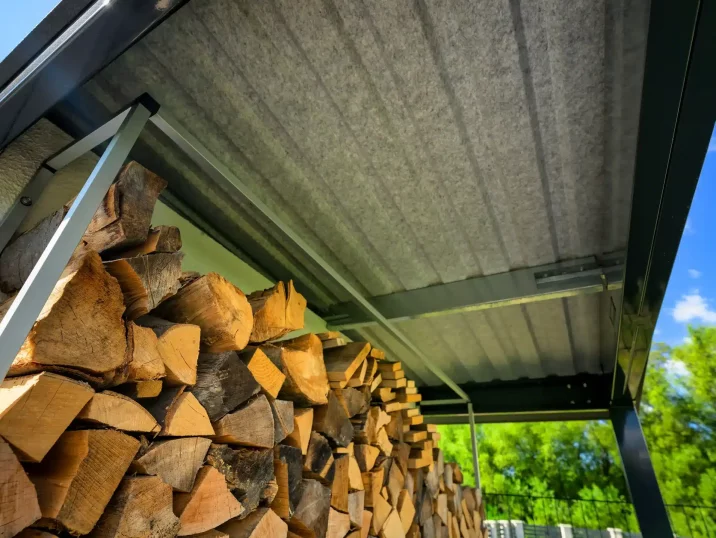 Holz wird unter einer Überdachung gelagert, geschützt vor Regen und Feuchtigkeit.