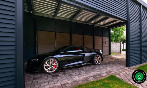 Luxuriöser schwarzer Sportwagen unter einem Metallcarport.