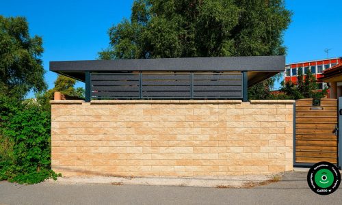 Außenansicht eines Carports hinter einer Steinmauer.