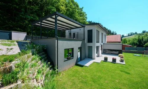 Pergola mit anthrazitfarbener Stahlkonstruktion und Pultdach am Einfamilienhaus.