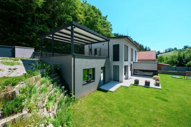 Pergola mit anthrazitfarbener Stahlkonstruktion und Pultdach am Einfamilienhaus.