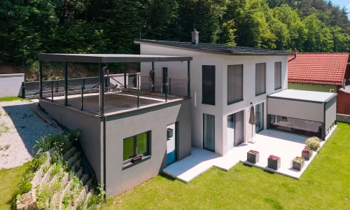 Anthrazitfarbenes Carport integriert auf einem erhöhten Untergrund.