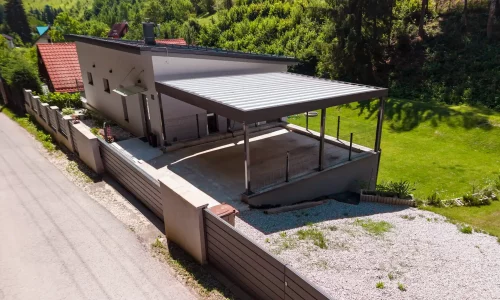 Luftansicht eines Carports mit Trapezblech-Dach am weißen Einfamilienhaus.