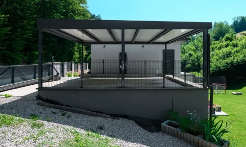 Carport mit anthrazitfarbenem Flachdach auf erhöhter Terrasse am Garten.