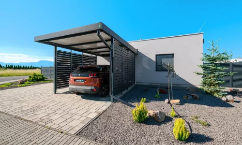 Anthrazitfarbenes Vordach mit Metallfüllung und geparktem SUV am Einfamilienhaus.