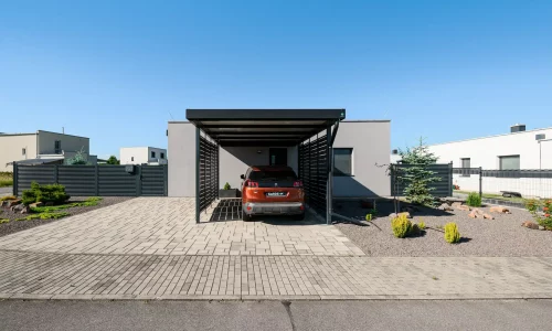 Anthrazitfarbenes Vordach mit Metallfüllung am Einfamilienhaus mit geparktem Auto.