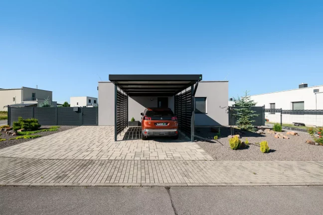Anthrazitfarbenes Vordach mit Metallfüllung am Einfamilienhaus mit geparktem Auto.