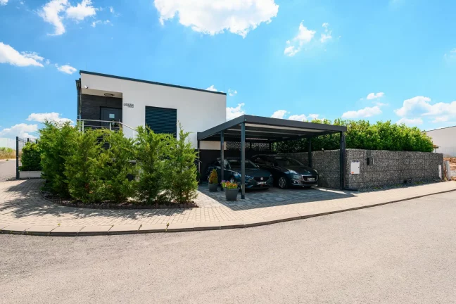 Anthrazitfarbenes Flachdach-Carport für zwei Fahrzeuge am Einfamilienhaus.