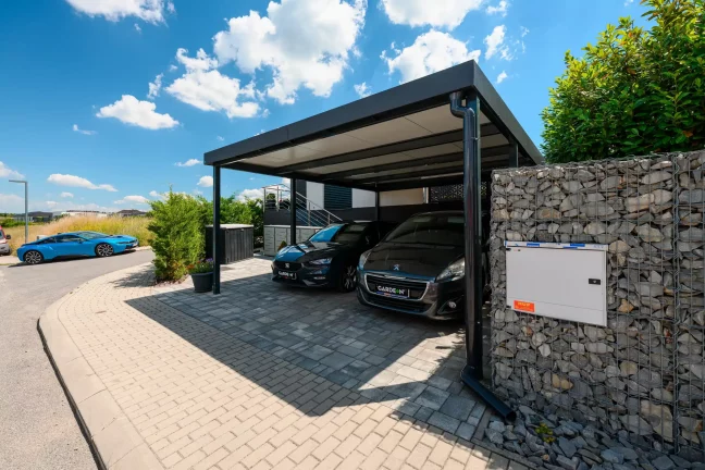 Doppelcarport in Anthrazit für zwei Autos an gepflasterter Zufahrt.