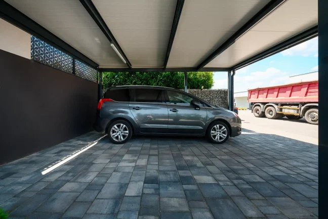 Innenansicht eines anthrazitfarbenen Carports mit gedämmtem Dach und geparktem Fahrzeug.