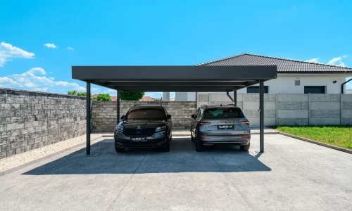 Anthrazitfarbener Doppelcarport mit Flachdach am Einfamilienhaus schützt zwei SUV.