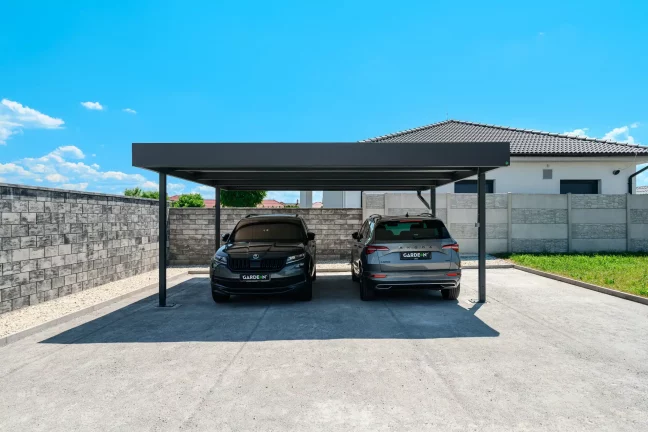Anthrazitfarbener Doppelcarport mit Flachdach am Einfamilienhaus schützt zwei SUV.