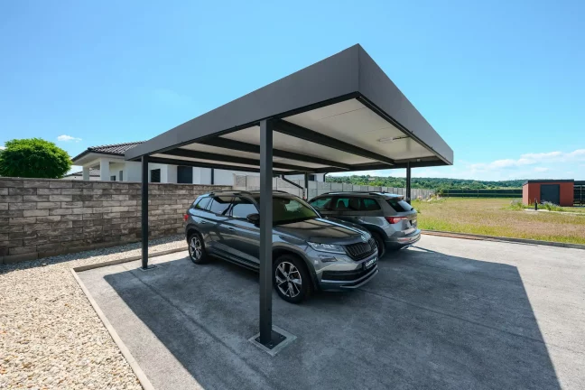 Flaches anthrazitfarbenes Carportdach schützt zwei SUV am Einfamilienhaus.
