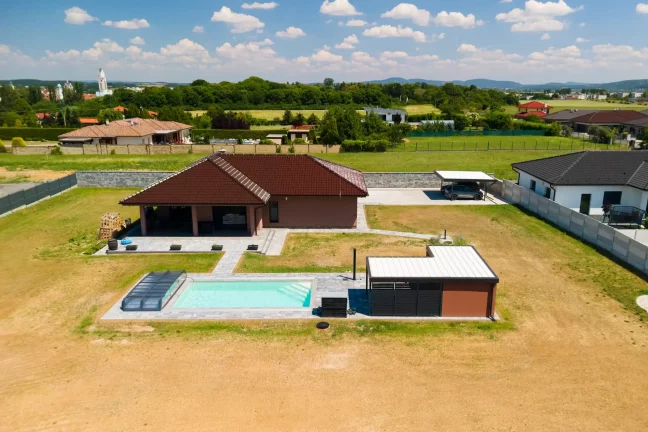 Luftaufnahme des Grundstücks mit Doppelcarport und Gartenhaus am Pool.