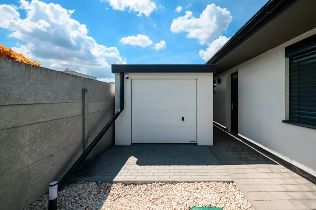 Weiße Garage mit Pultdach und weißem Sektionaltor