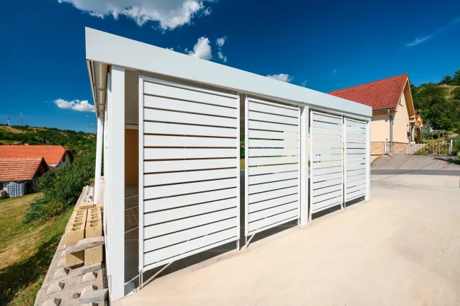 Carport mit weißer horizontaler Metallverkleidung bei einem Einfamilienhaus.