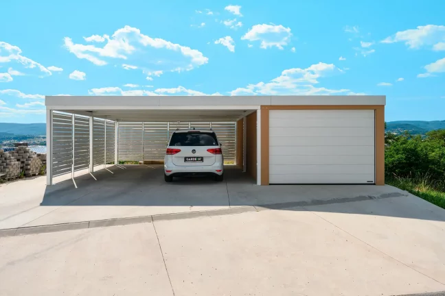 Weiße Metallverkleidung des Carports mit angeschlossener Garage mit Ziegelputz und Sektionaltor.
