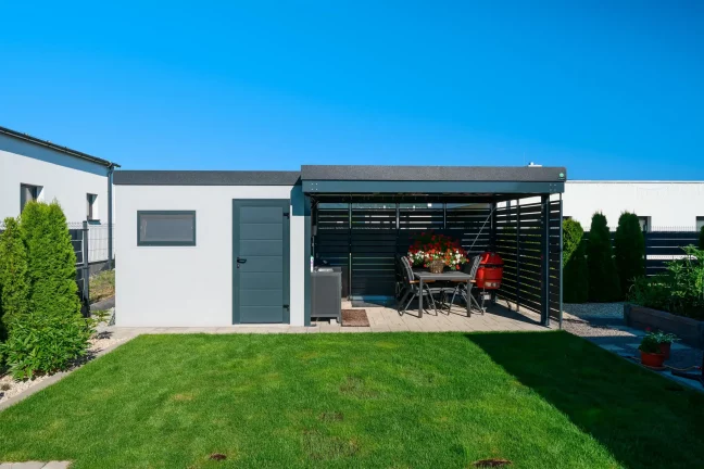 Gartenhaus mit weißem Putz und Vordach mit anthrazitfarbener Metallfüllung.