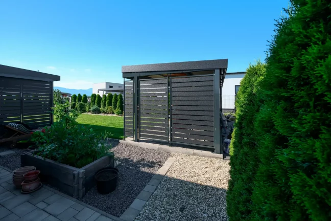 Gartenhaus mit anthrazitfarbener Metallfüllung der Wände im Gartenbereich.