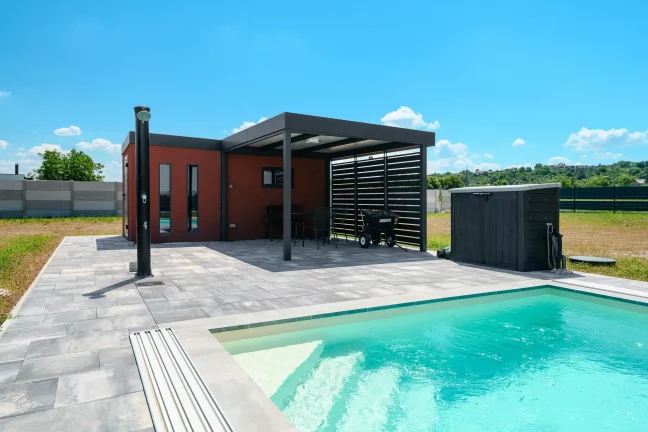 Gartenhaus mit KABE Putz und Lamellencarport am Pool.