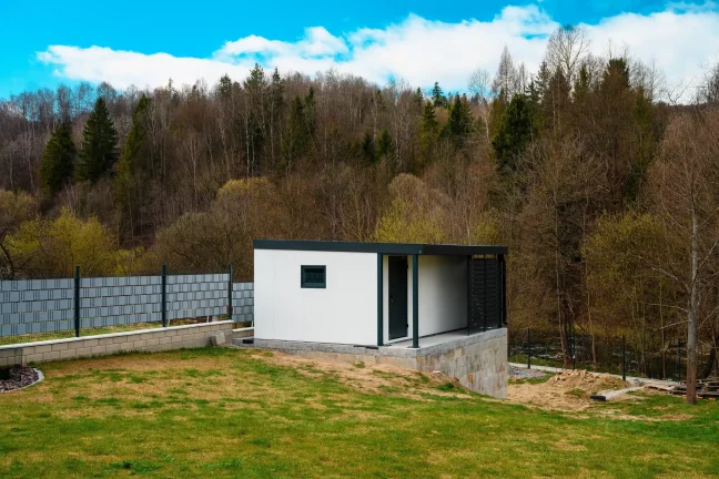 Weißes Gartenhaus mit Pultdach und seitlicher Überdachung