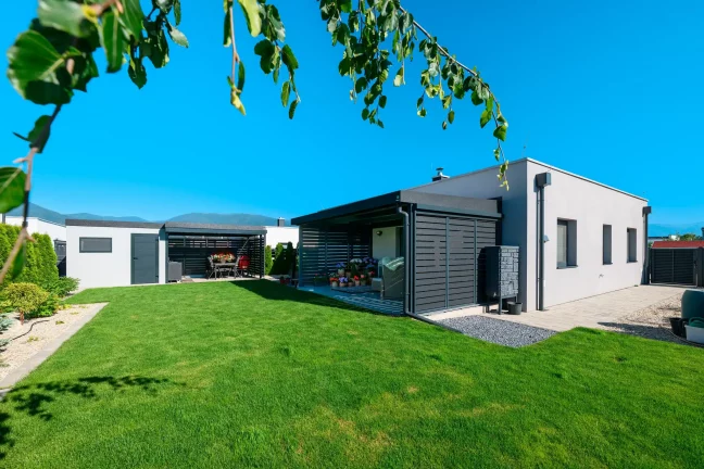 Anthrazitfarbenes Carport mit Metallfüllung am Einfamilienhaus mit Garten.