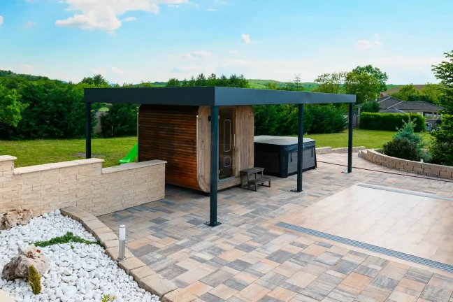 Anthrazitfarbene Pergola am Pool mit transparenter Abdeckung, weißer Kies und gepflasterte Fläche rundherum