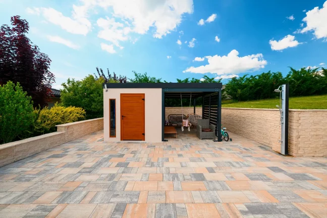 Gartenhaus mit braunen Türen und Überdachung am Pool, gemauerte Steineinfassung