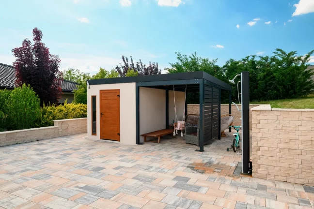 Gartenhaus mit Türen und anthrazitfarbener Überdachung, gepflegter Garten mit Ziersträuchern