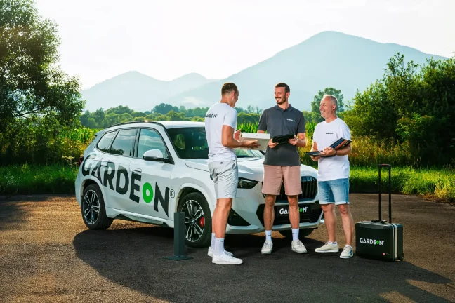 GARDEON-Team-Treffen mit Musterbüchern und Koffer vor dem Marken-BMW.