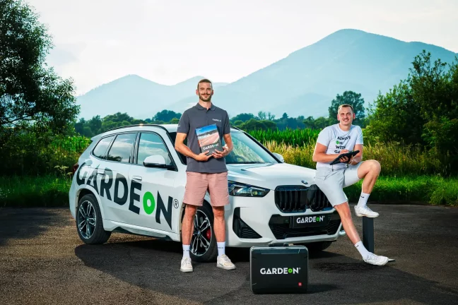 Zwei GARDEON-Mitarbeiter mit Musterbuch und Tablet vor dem Firmen-BMW.