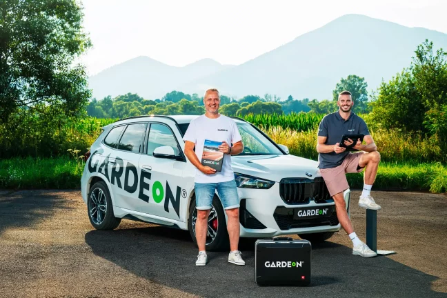 Zwei GARDEON-Agenten mit Musterbuch und Tablet am Firmen-BMW.