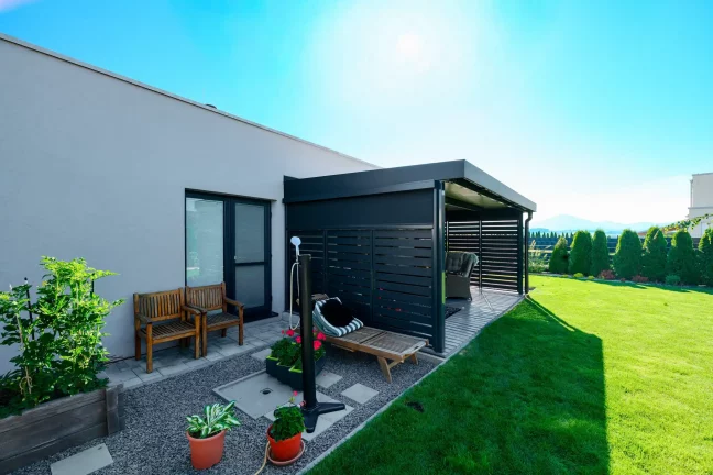 Anthrazitfarbene Pergola mit Metallfüllung im Garten eines Einfamilienhauses.