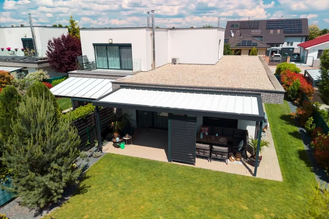 Luftaufnahme einer Pergola mit weißem Dach und anthrazitfarbener Konstruktion, grüner Rasen